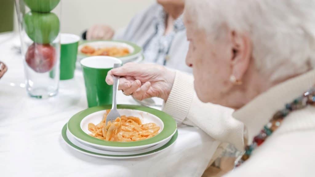 senior woman eating pasta