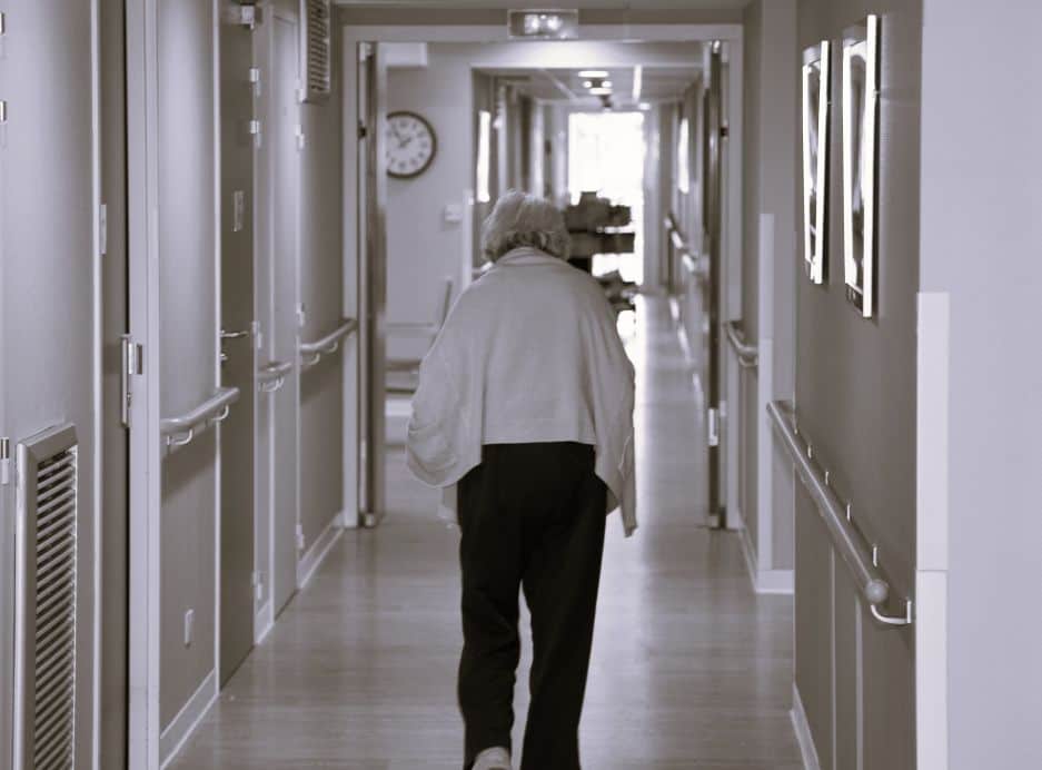 elderly woman walking alone toward nursing home exit